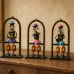 Set of three handcrafted Rajasthani-style metal figurine wall decor panels with colorful traditional attire, displayed on a table and mounted on a wall.
