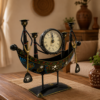 Decorative handcrafted metal boat-shaped table clock with colorful traditional Indian artwork, displayed on a wooden living room table.