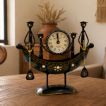 Decorative handcrafted metal boat-shaped table clock with colorful traditional Indian artwork, displayed on a wooden living room table.