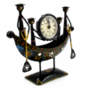 Decorative handcrafted metal boat-shaped table clock with colorful traditional Indian artwork, displayed on a wooden living room table.