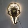 Decorative elephant face wall art with an ornate golden crown and traditional Indian detailing, displayed in a rustic stylish living room.