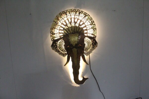 Decorative elephant face wall art with an ornate golden crown and traditional Indian detailing, displayed in a rustic stylish living room.