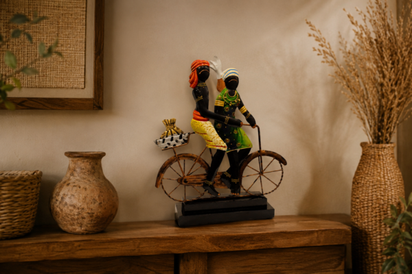 Handcrafted Rajasthani couple riding a bicycle, featuring colorful traditional attire and detailed metalwork on a decorative black base.